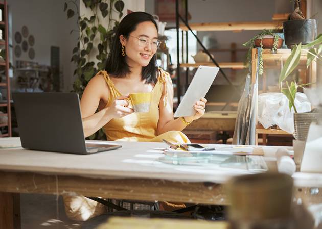 Asian woman small business owner at desk looking at a small business strategy on a tablet